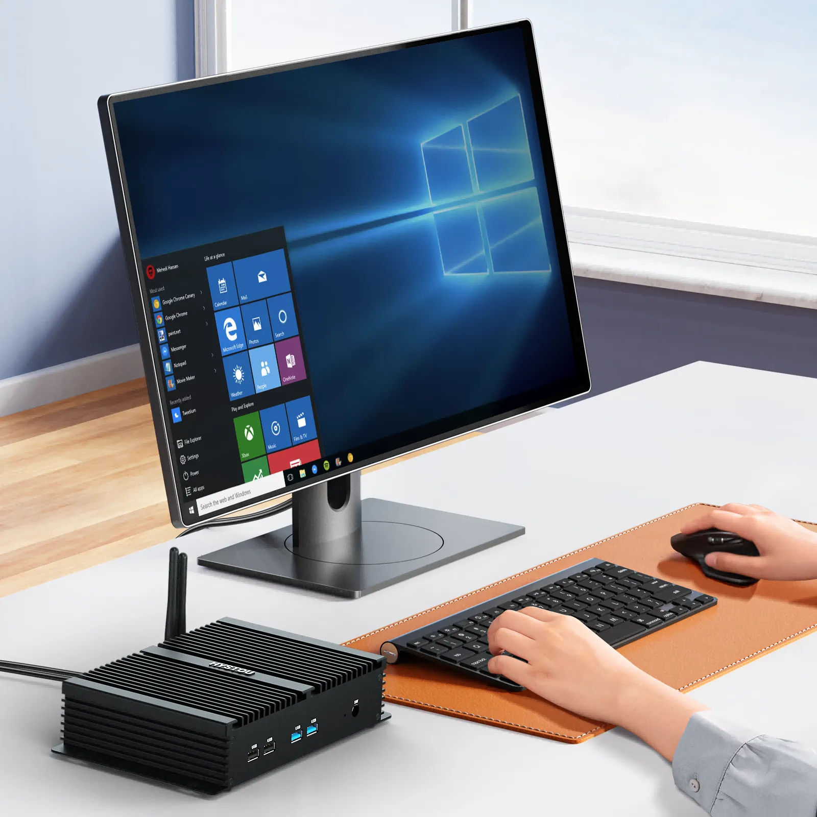 K4 fanless mini PC connected to a computer monitor on a clean desktop workstation.